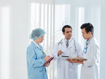 Serious doctors discussing article on tablet computer with colleagues and explaining them what to do during epidemic period